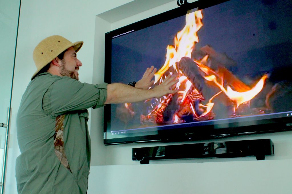 Intrepid explorer warming his hands on a TV fire