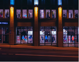 Nighttime scene of a store front with a gym above it.