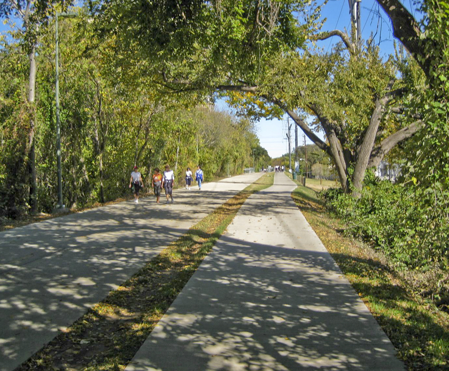 Photo of a peaceful day on the Katy Trail. People walking along trail with trees overhanging the trail.