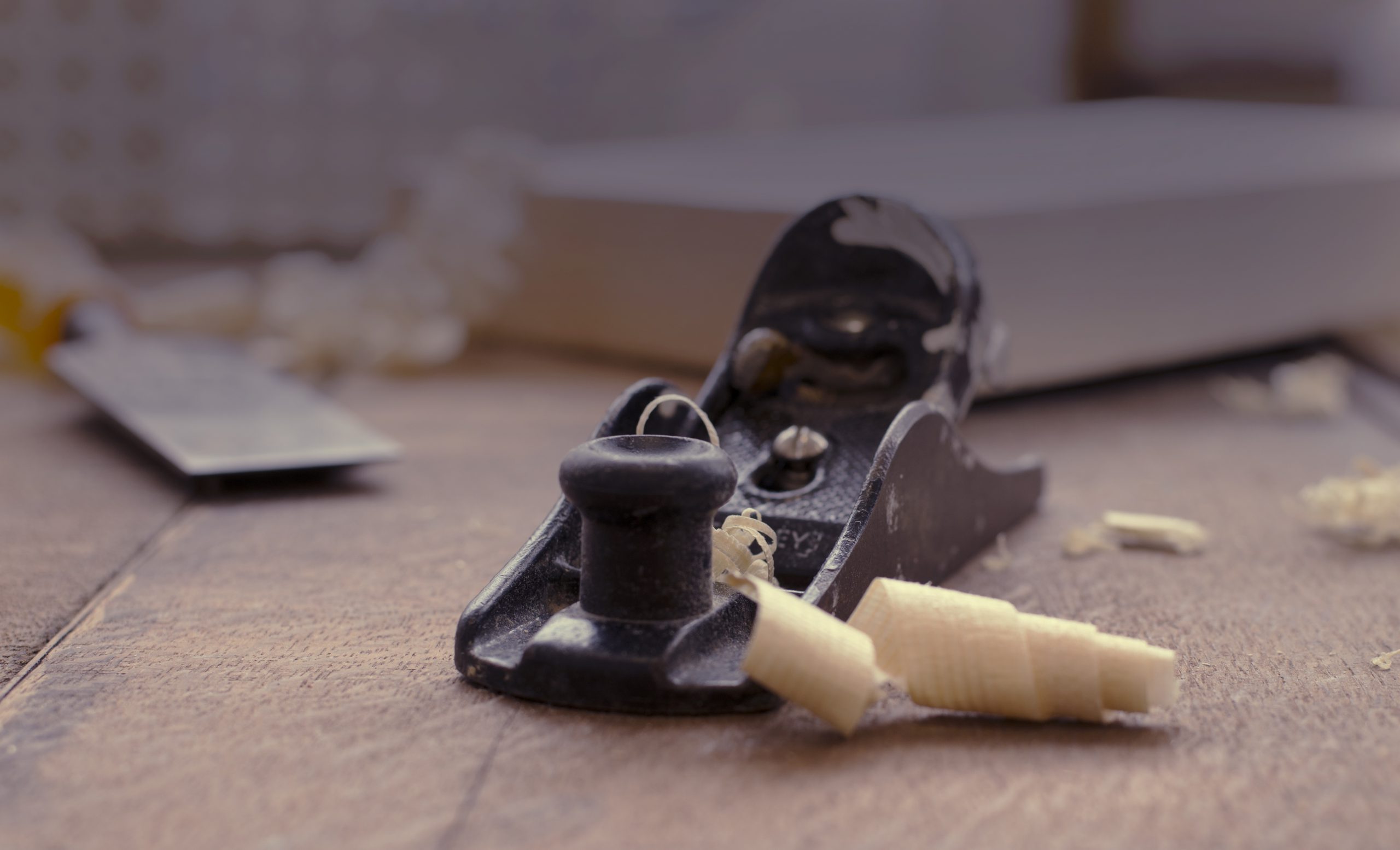Photo of a block plane with wood shavings coming out of the plane's mouth