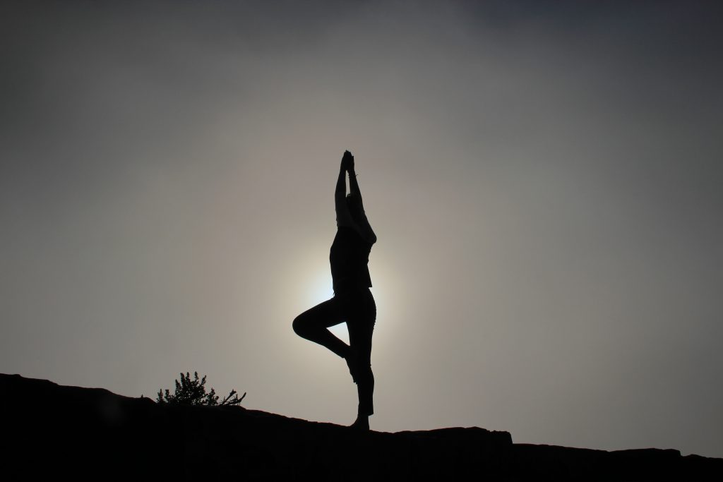 Woman doing a yoga pose in front of the sun